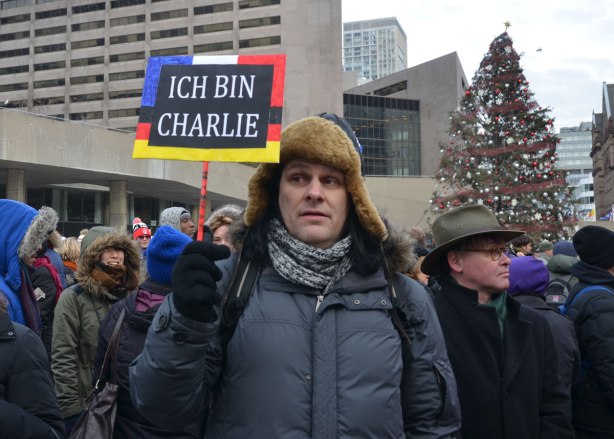 A man is holding a sign that says Ich Bin Charlie 