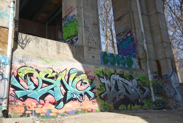 graffiti on the concrete supports under a bridge - colourful tags.  Some are older and are starting to peel