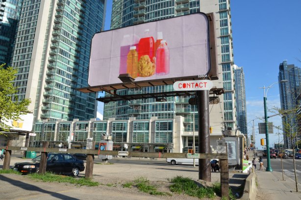 a billboard with a large picture of clear bottles filled with coloured liquids in reds and oranges. 