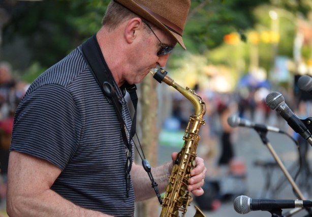 saxophone player playing in front of many microphones at an outdoor music festival