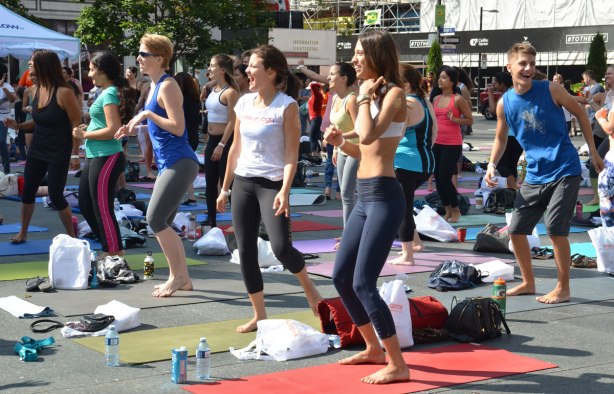 men and women at a yogathon - doing yoga outside in a large group