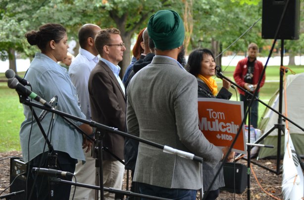 A group of NDP candidates from the GTA including Andrew Cash, Peggy Nash, Akil Sadikali, and Jennifer Hollett,are standing together. Olivia Chow is addressing the small crowd that has come to the rally to repeal Bill C 51. One of the candidates is holding a Tom Mulcair sign. 
