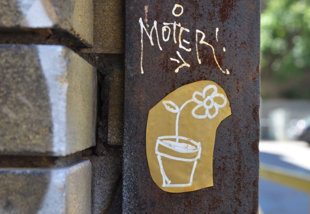 on a rusty metal pole beside a brick wall, close up of a flower in a flower pot line drawing in white on brown paper with the word moter in white above it with an arrow pointing to the flower