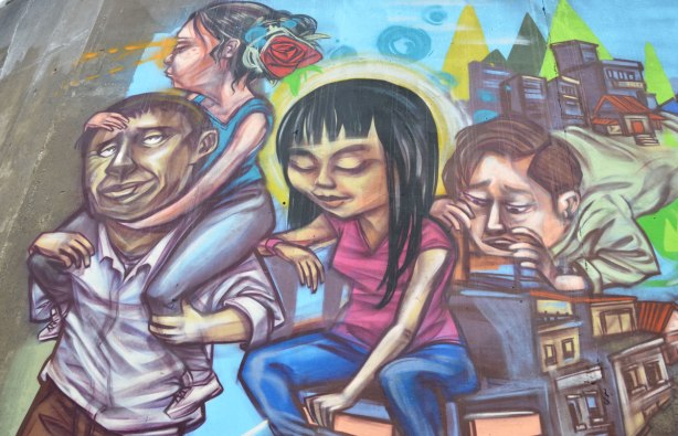 part of a mural by elicser, a group of 4 people, 2 men and 2 women. One of the women is on the shoulders of one of the men. 