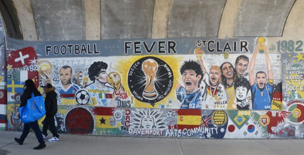 part of a mural with a soccer theme with words that say Football Fever St. Clair 1982. also with pictures of football players and flags from different countries. 