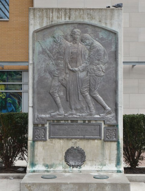 A memorial to British nurse Edith Clavell and the Canadian nurses of WW1, a bronze plaque mounted on a stone tablet. Picture of Clavell between two upright but wounded soldiers. 