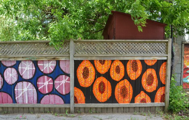 two sections of wooden fence painted, one with pink circles and the other with orange ovals