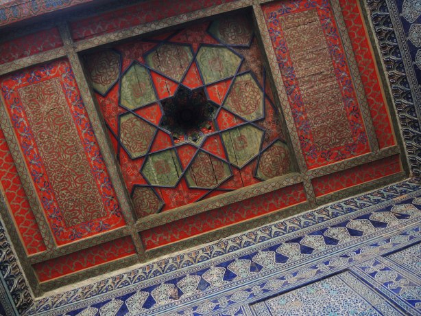 painted wood ceiling in an old building in Khiva, the harem of the castle, in red and green, octagonal pattern, some of the walls are also showing, they are covered in blue and white tile 