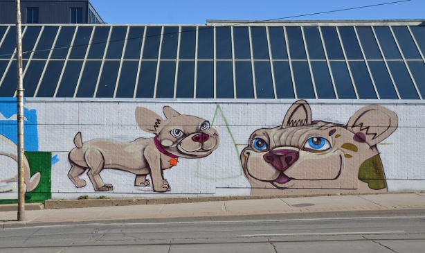 two dogs painted on a mural that isn't quite finished, on the side of a building, 