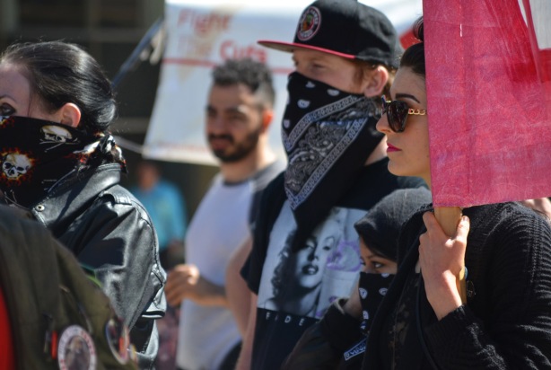 people at a protest rally, two people have a bandanas over their faces