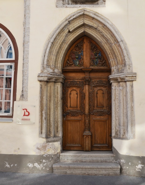 old carved wooden door with stone gothic arch around it. Now a restaurant in Tallinn, Bordoo restaurant