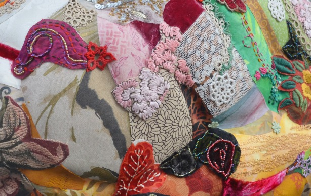 close up of a fabric collage on a sculpture, bits of fabric with flowers on it, some embroidered leaves and flowers, lace and trim too, 