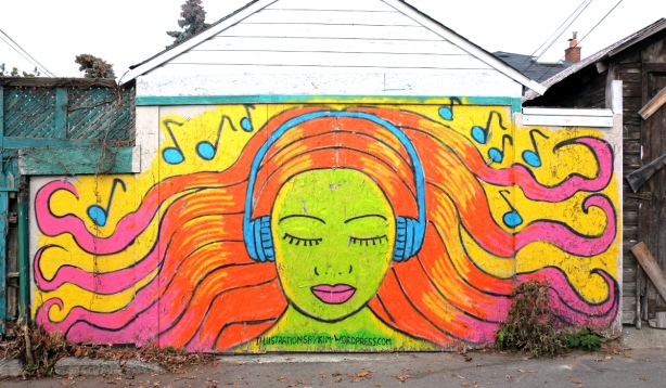 garage door painted with a mural of woman with light skin skin and orange and pink hair with eyes closed and wearing blue headphones. music notes around her head
