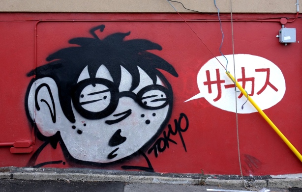 mural by Tokyo, red background with black and white boys face, and white word bubble with red Japanese characters written inside