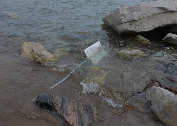 sign fallen over and under water, surrounded by rocks, Lake Ontario 