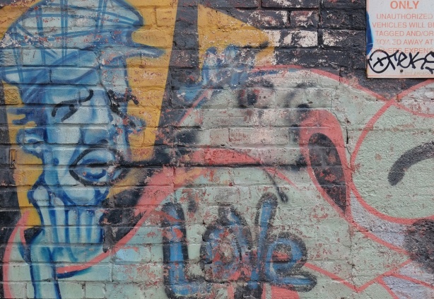 old street art, paint fading, of a blue man's face, and the word love 