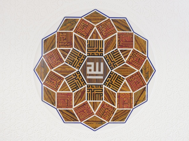 medallion of stone, calligraphy, arabic, on a white wall 