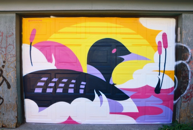 mural on a garage door of a loon swimming into the sunset