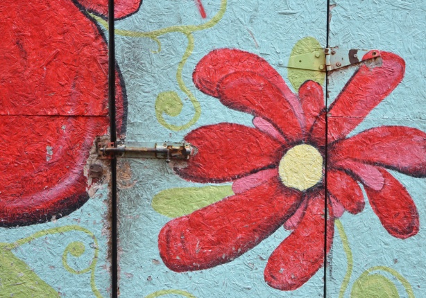 particle board door on a shed, painted pale blue and with a large red flower 