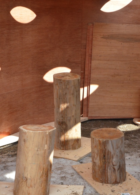 three wood stumps stand upright on the ground, interior of art installation