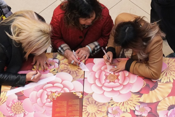 three women writing on pink ribbons
