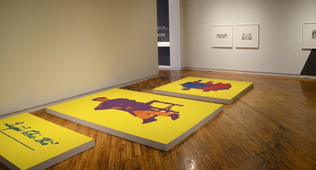 art gallery room with three large canvases on the floor, all wth bright yellow backgrounds