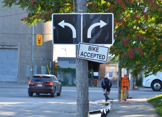 black and white arrow direction signs traffic signs, right lane turns right and left lane turns left. Also sign that says bike accepted. 