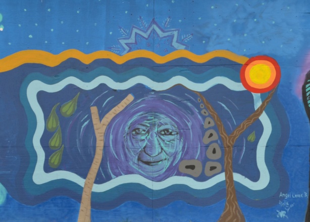 mural, an old woman's face in the middle, stylized brown trees, lines for earth and sky
