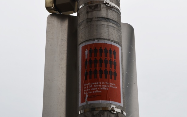 a poster on a metal utility pole with a graphi to illustrate how black people are more likely to be shot and or killed by the Toronto police 