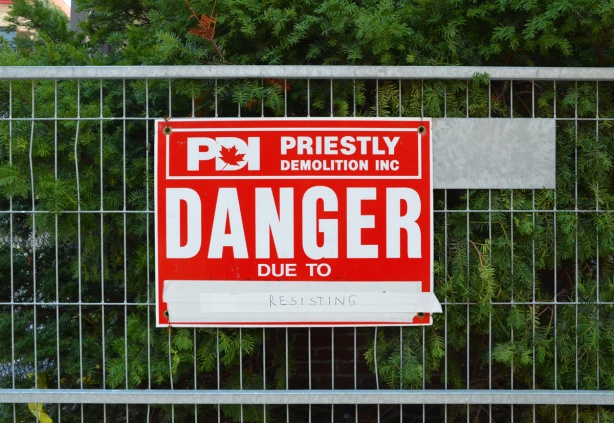 red and white danger due to sign, altered to say Danger due to resisting