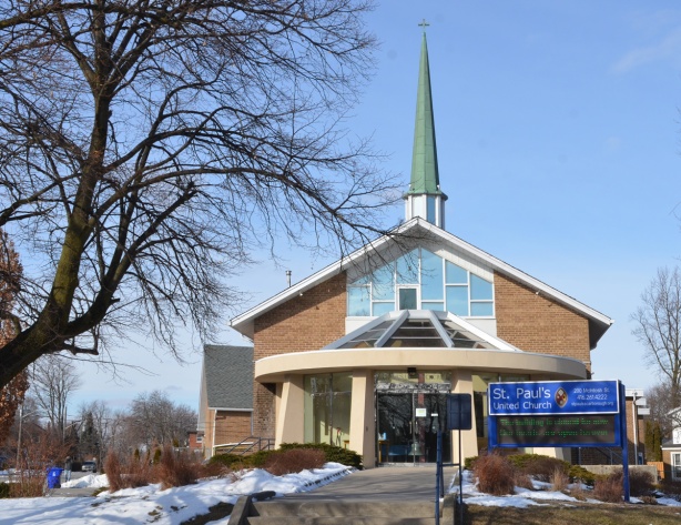 front of St. Pauls United Church in Cliffside Scarborough, narrow green steeple, round glass entranceway, stairs leading from the sidewalk to the church 