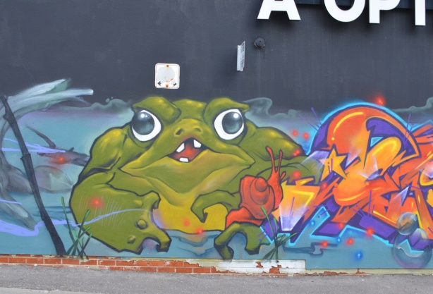 street art mural of a large lumpy green frog and an orange snail
