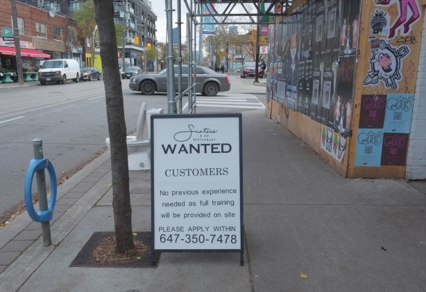 sign on sidewalk that says wanted, customers