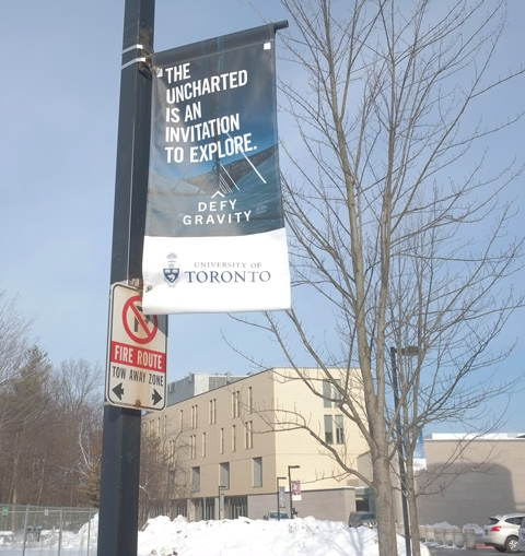 banner on light standard at University of Toronto Scarbourgh Campus that says the uncharted is an invitation to explore 