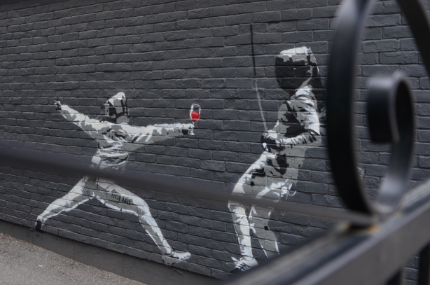 mural of two fencers, one with a glass of red wine in their hand 