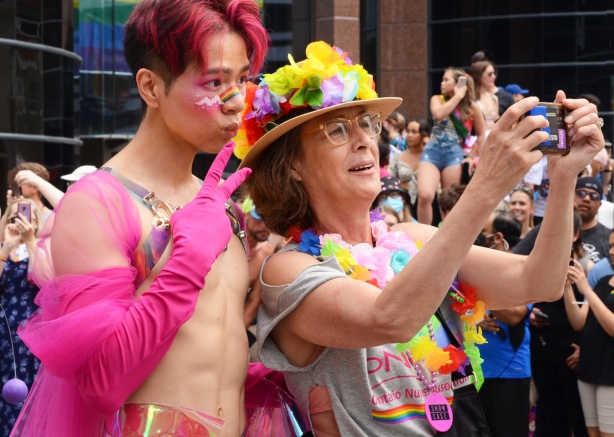 Toronto Pride Parade 2022, start of route, man in long pink gloves posing with woman in hat with flowers on it