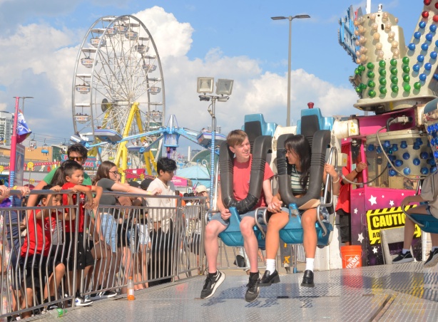 a young couple are harnassed into a ride at the cne while they wait for it to start