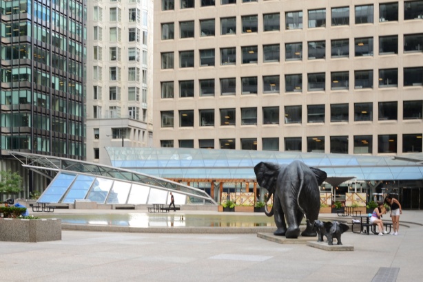 elephant statues, adult and two little ones, surrounded by tall buildings
