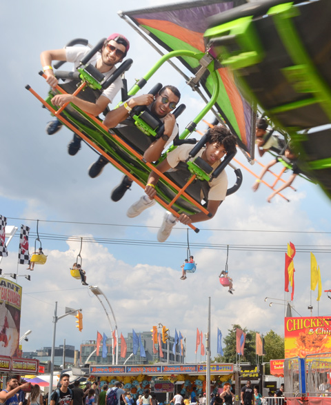 three young men on a flying ride over the midway at the c n e 
