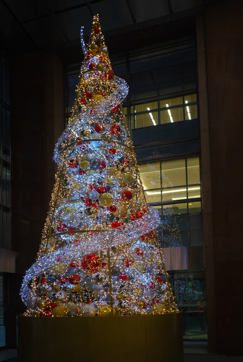 tall christmas tree in an office building lobby, made of red, gold and silver shiny balls on an inverted cone metal frame, 
