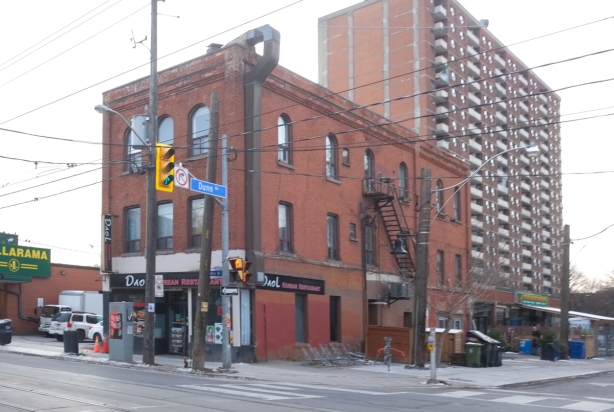 old brick building at the corner of Dunn and Queen, with newer highrise behind