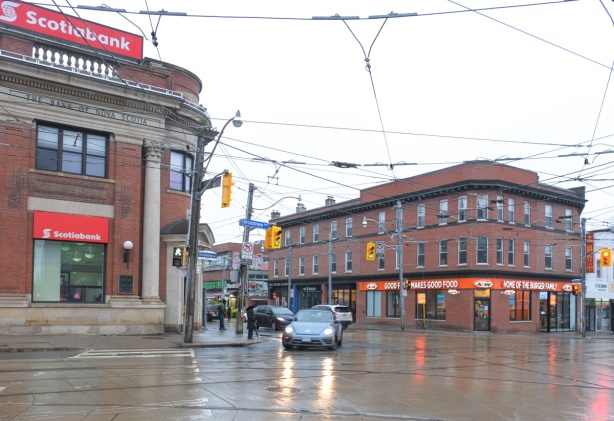 looking east from Broadview, Scotiabank on the north side of Gerrard and A & W burger restaurant fast food on the south side, both in old brick buildings, rainy day, wet pavement