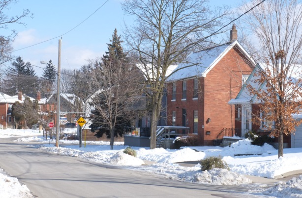 winter residential street scene, older brick house, snow, trees, blue sky 