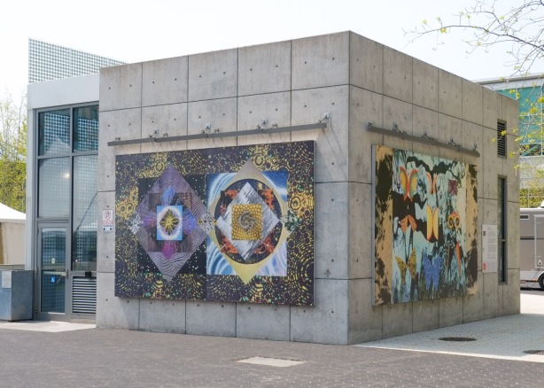 Cubic concrete structure at Ontario Square, two sides visible, each with a large image by Maggie Groat, part of Double Pendulum