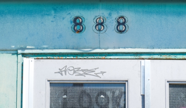 old numbers on a building, 888, removed but traces left behind, on a teal coloured wall 