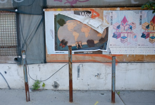 posters on the wall of a construction site including a large map of the world with pairs of baby shoes around it (large photo)