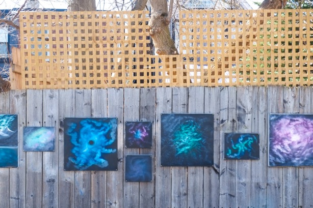  few paintings in blues, purples, and teals, abstracts, mounted on wood fence on Craven Rd., 