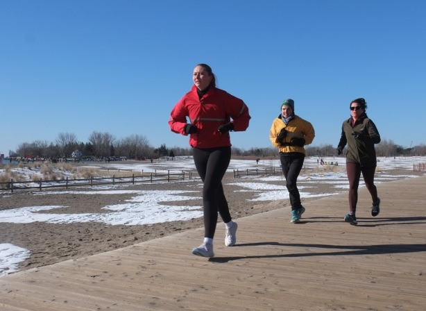 three young people jogging on the boardwalk at woodbine beach
