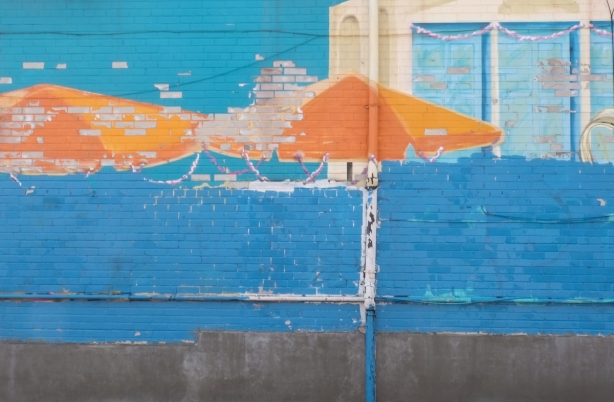 an old mural with orange umbrellas that has had the bottom painted over in blue