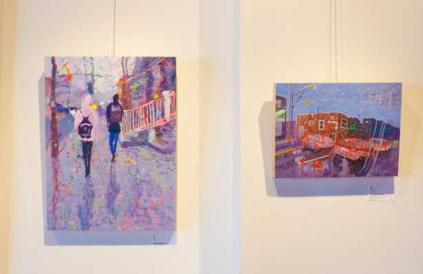 two paintings on gallery wall, riverdale Hub, both are rainy day scenes, one has two people walking on a sidewwalk, with a black backpack, the other is looking out onto an intersection